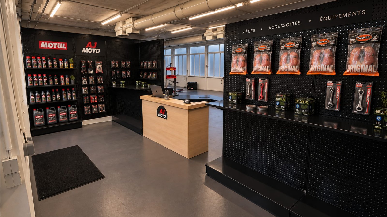 Accueil de l’atelier AJ Moto : comptoir, rayon d’huiles Motul et panneaux de pièces, accessoires et équipements